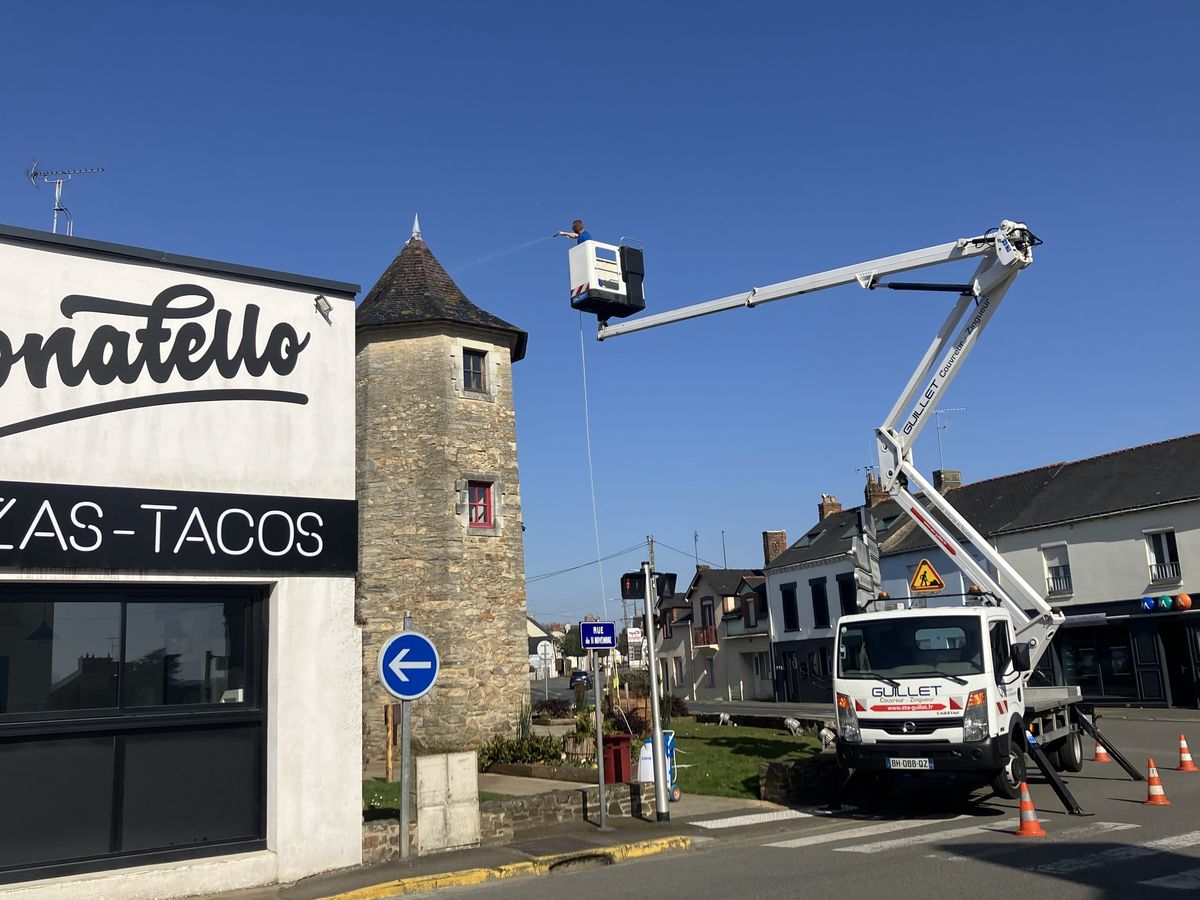 Camion nacelle d'ETS Guillet déployé au pied d'une tour couverte en ardoise, en centre-bourg