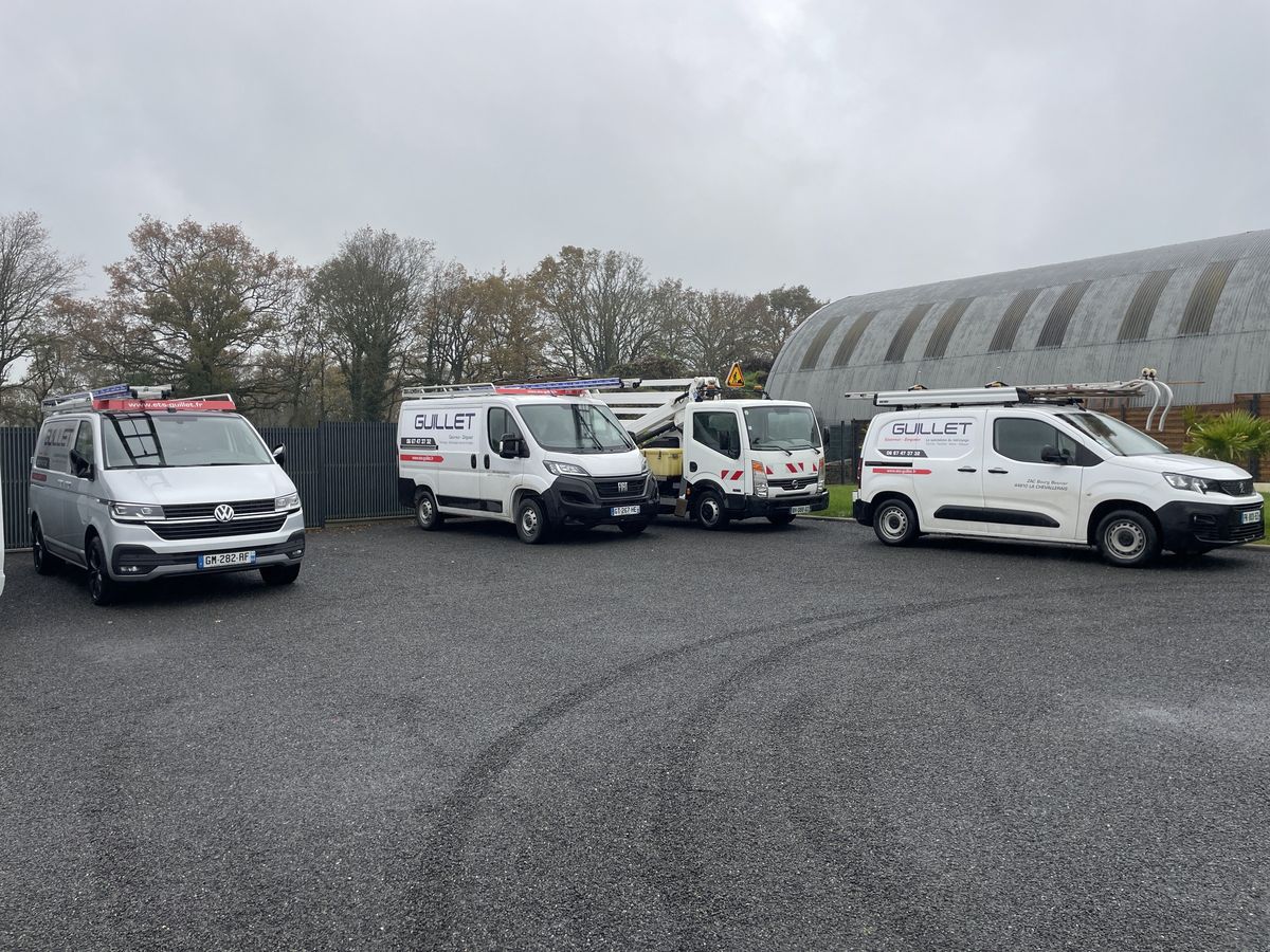 Quatre véhicules d'ETS Guillet alignés au dépôt, dont un camion nacelle